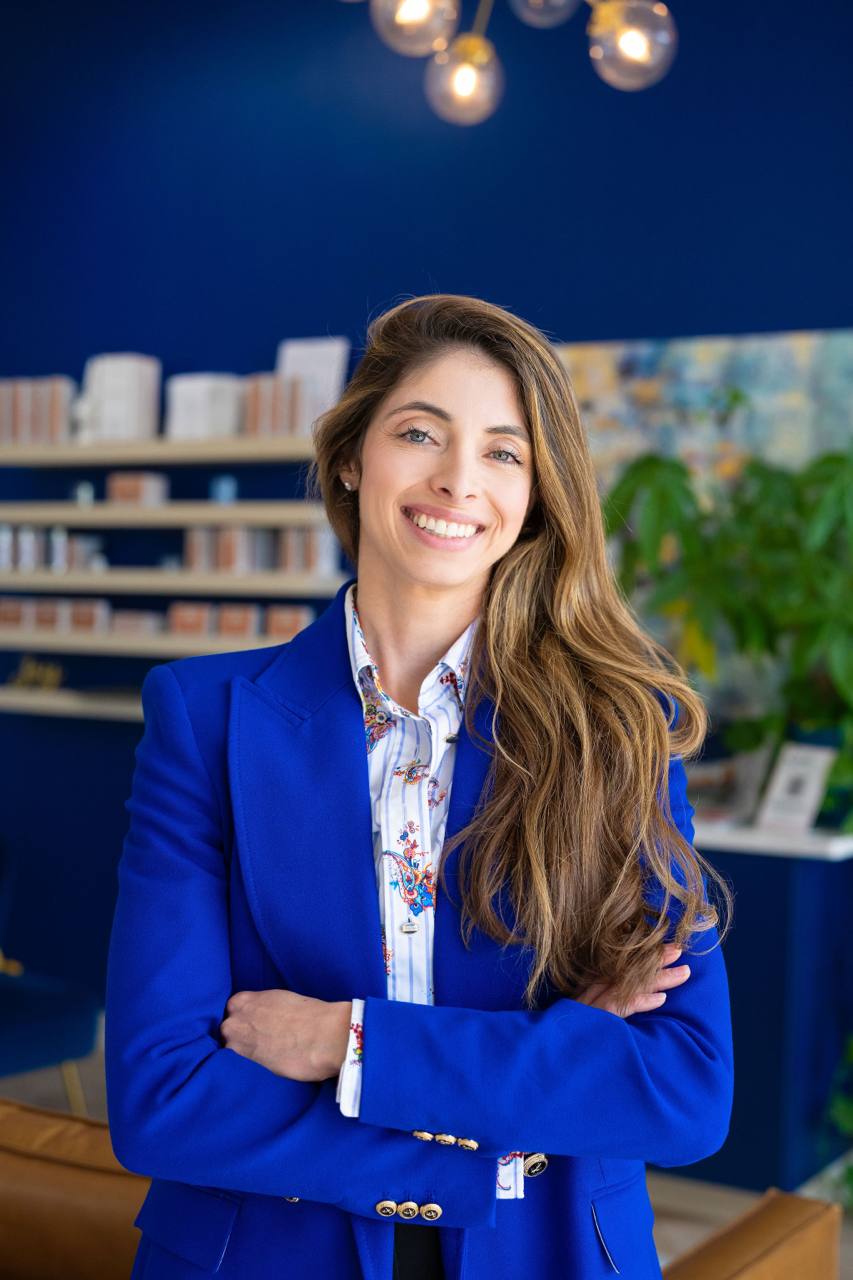 Dr. Celesta Ferreira in a cobalt blazer, smiling in her clinic